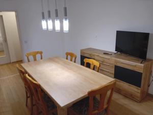 a dining room with a wooden table and a flat screen tv at Geräumige FeWo nahe Nürnberg in Oberasbach