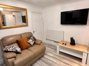 a living room with a brown couch and a table at One small bed apartment by monishortlets in Dagenham