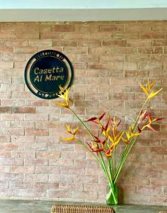 a vase with flowers in front of a brick wall at Casetta Al Mare in Dauin