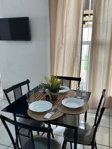 a dining room table with two chairs and a black table with plates at Apartamento inteiro Varzea Grande MT in Várzea Grande