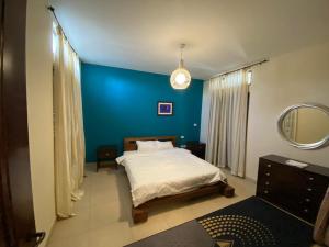 one bedroom apartments aqaba on 2 swimming pool Tala bay في العقبة: غرفة نوم بسرير وجدار ازرق