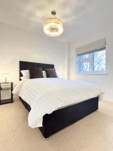 a white bedroom with a large bed and a chandelier at Luxury London Two Bedroom Apartment in West Dulwich