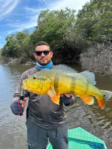 a man holding a large yellow fish in the water at Amazon Extreme River Fish in Manaus