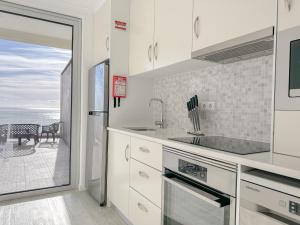 uma cozinha com armários brancos e vista para o oceano em South Shore 2 - HOST & CHILL em São Roque