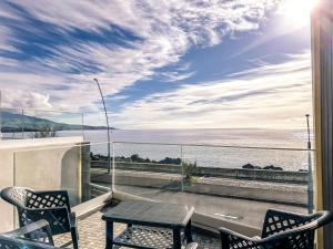 einen Tisch und Stühle auf einem Balkon mit Meerblick in der Unterkunft South Shore 2 - HOST & CHILL in São Roque