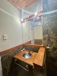 a bathroom with a sink and a stone wall at La maison in Caviahue