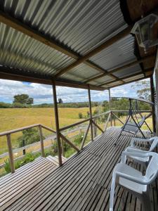 a deck with two chairs and a view of a field at Los avellanos in Chonchi
