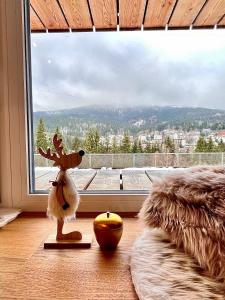 a reindeer statue in a room with a large window at ALPINA NEW apartment in the mountains in Špindlerův Mlýn