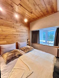 a large bed in a room with a wooden wall at ALPINA NEW apartment in the mountains in Špindlerův Mlýn