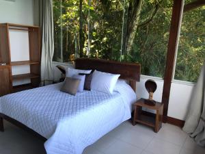 a bedroom with a bed in front of a window at Deck da Villa Picinguaba in Ubatuba