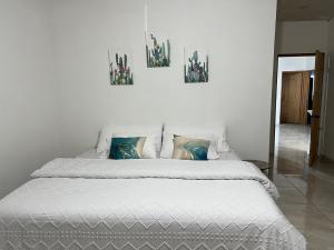 a white bed with three pictures on the wall at Puerto San Carlos Bay House & Tours -1st Floor- in San Carlos