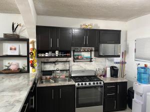 a kitchen with black cabinets and a stove top oven at Puerto San Carlos Bay House & Tours -1st Floor- in San Carlos