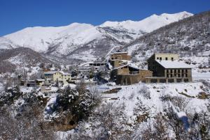 un pueblo cubierto de nieve con montañas en el fondo en Apartamentos Casa Masover en Buira