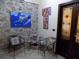 una stanza con due sedie e un tavolo e un dipinto sul muro di Archi di San Giacomo a Cammarata
