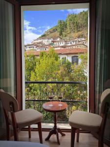 Habitación con mesa, sillas y ventana grande. en Villa Mishel Suites en Berat