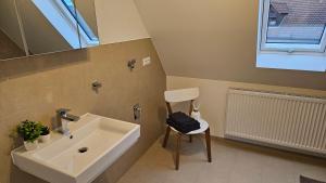 a bathroom with a sink and a chair and a mirror at FeWo AS 5 One Bamberg in Hallstadt