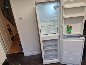 an empty refrigerator with its door open in a kitchen at Oasis Abode @Shiremoor 