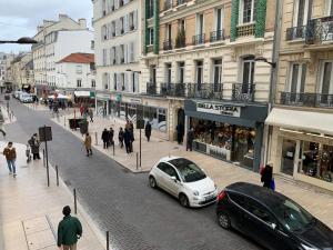 a street with cars parked on a city street at Elegant Central Vincennes Paris in Vincennes