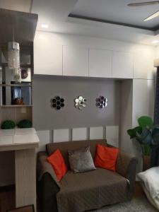 a living room with a couch with orange pillows at Mesaverte Residences T2-8H in Cagayan de Oro