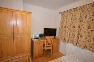 a bedroom with a desk with a computer and a curtain at Large Ensuite room in Oxford