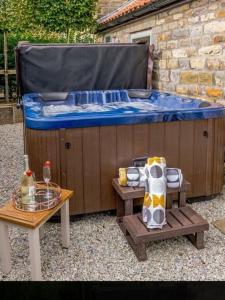 a hot tub sitting next to a wooden table with a table at Bees cottage Luxury 5* Holiday cottage with Hot Tub in Scarborough