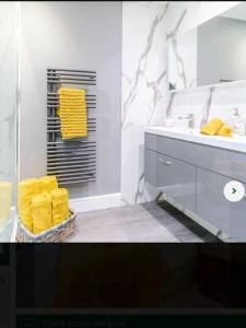 a bathroom with a sink and a mirror and yellow towels at Bees cottage Luxury 5* Holiday cottage with Hot Tub in Scarborough