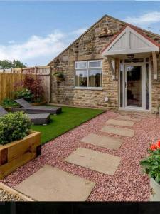 un patio trasero con una casa de piedra y un jardín en Bees cottage Luxury 5* Holiday cottage with Hot Tub, en Scarborough