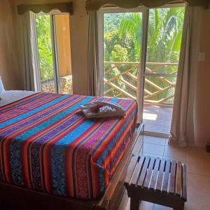 1 dormitorio con cama, banco y ventana en La Hacienda Belize Guest House en Benque Viejo del Carmen