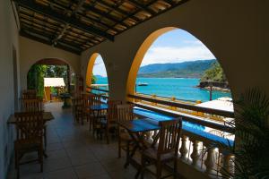 un restaurante con mesas y sillas y vistas al agua en Colonial Hotel, en Ilhabela