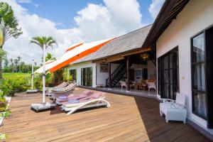 a wooden deck with lounge chairs and an umbrella at Villa Labak Sari Tabanan in Antasari