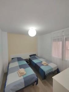 2 Einzelbetten in einem Zimmer mit einem Tisch in der Unterkunft Gandia centro reformado con clim F/C in Gandía