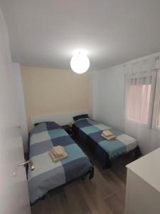 duas camas num pequeno quarto com uma luz em Gandia centro reformado con clim F/C em Gandia