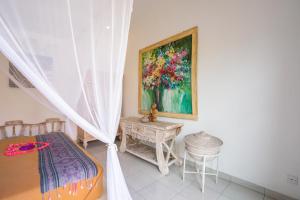 a bedroom with a painting on the wall and a table at Villa Labak Sari Tabanan in Antasari