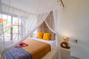 a bedroom with a bed with yellow pillows and a window at Villa Labak Sari Tabanan in Antasari