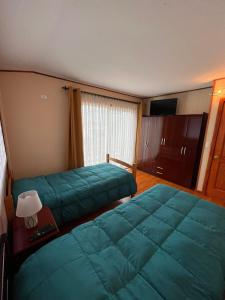 Habitación de hotel con 2 camas y TV de pantalla plana. en Hospedaje Brisas de Frutillar en Frutillar