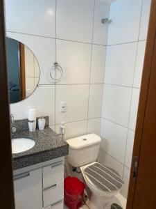 a bathroom with a toilet and a sink and a mirror at Apartamento completo Ilheus in Ilhéus