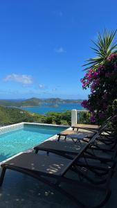 a swimming pool with two lounge chairs next to at COCONUT BREEZE VILLA: MESMERIZING VIEWS, COOLING TRADEWINDS in Coral Bay