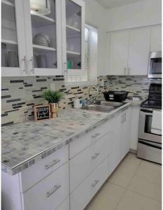 a white kitchen with white cabinets and a sink at BOOK ME, 3mins Hard Rock Stadium in Miami Gardens