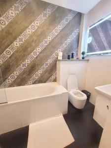 a bathroom with a tub and a toilet and a sink at HOUSE EMAH in Douala