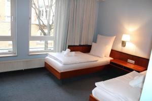 two beds in a hotel room with two windows at Hotel Mozart Bonn in Bonn