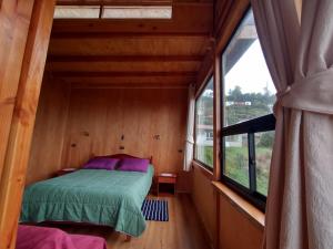 1 dormitorio con 1 cama en una habitación con ventana en Cabaña los arrayanes full equipada en Valdivia