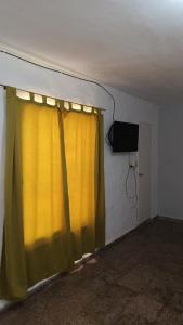 Habitación con cortina amarilla y TV en Departamento para 2 personas en Bialet Massé