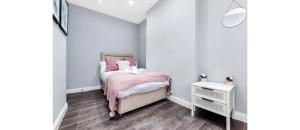 a small bedroom with a bed and a night stand at Sleek Modern 3BR Flat in Nunhead in London