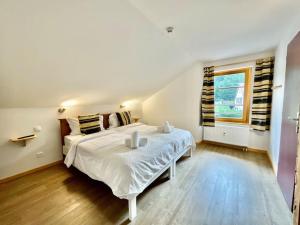 Un dormitorio con una gran cama blanca y una ventana en Le Grand Loup, appartement neuf avec bain nordique, en Gerbépal