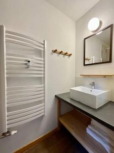 y baño con lavabo blanco y espejo. en Le Grand Loup, appartement neuf avec bain nordique, en Gerbépal