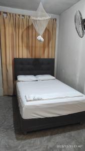 1 dormitorio con 1 cama con sábanas blancas y ventana en La casa de Joan, en Máncora