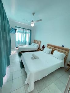 a bedroom with two beds and a ceiling fan at Hotel Plama Cana in Sosúa