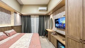 a bedroom with a bed and a flat screen tv at Casa de Parco near ICE BSD AEON Mall - Wabi Sabi in Samporo +8 photos