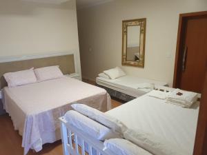サン・ガブリエウにあるPousada Familiarのベッド2台と鏡が備わる客室です。