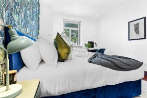 ein Schlafzimmer mit einem weißen Bett mit Kissen in der Unterkunft Enchanted Oasis: A Cozy Flat w/ Botanical Charm in Hanwell
